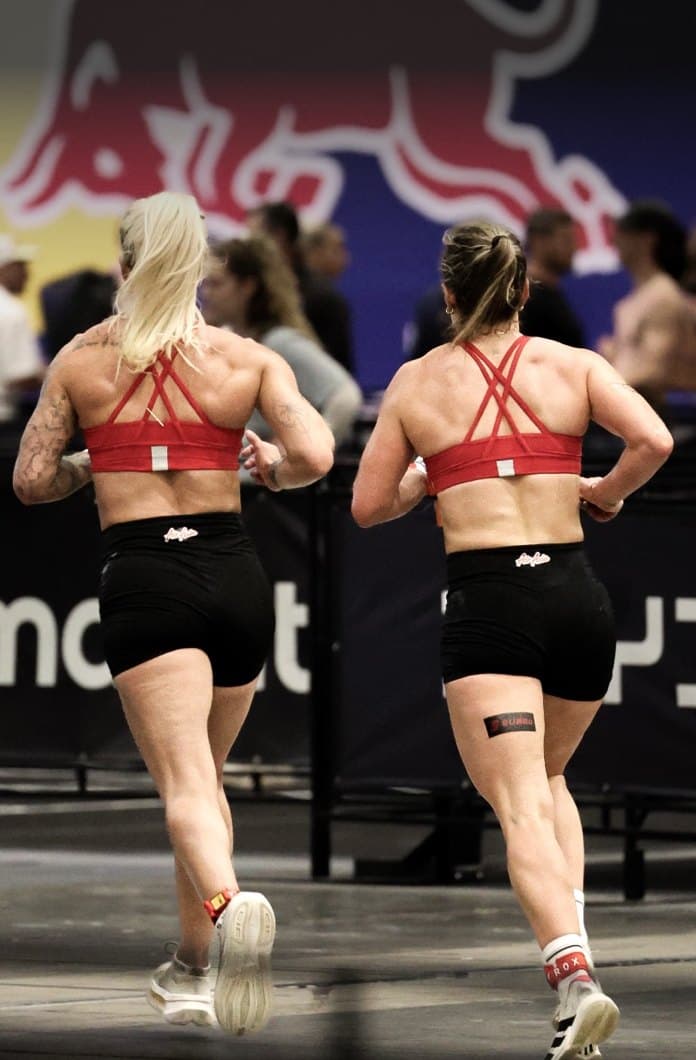 Two athletes running the course side by side, in step